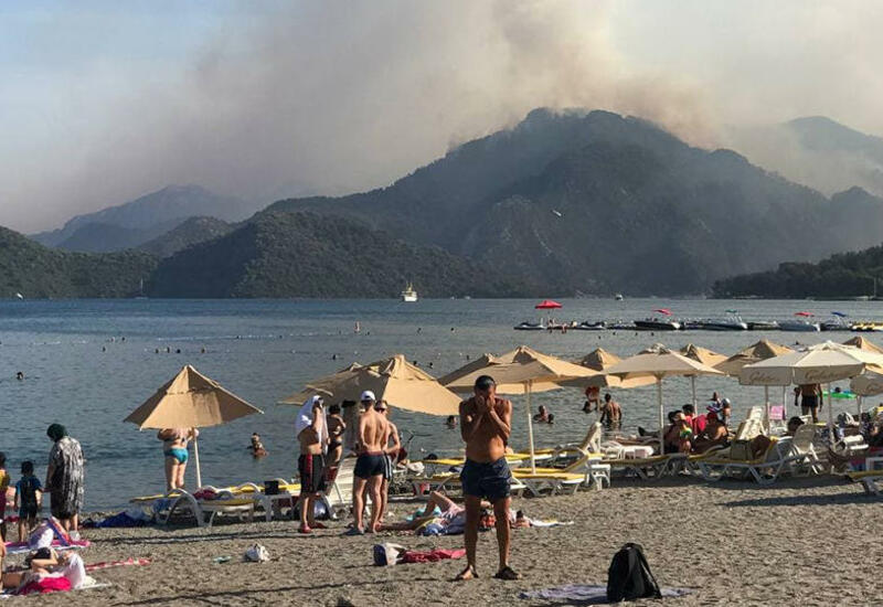 Туристы продолжают плавать в море, несмотря на лесные пожары в Турции