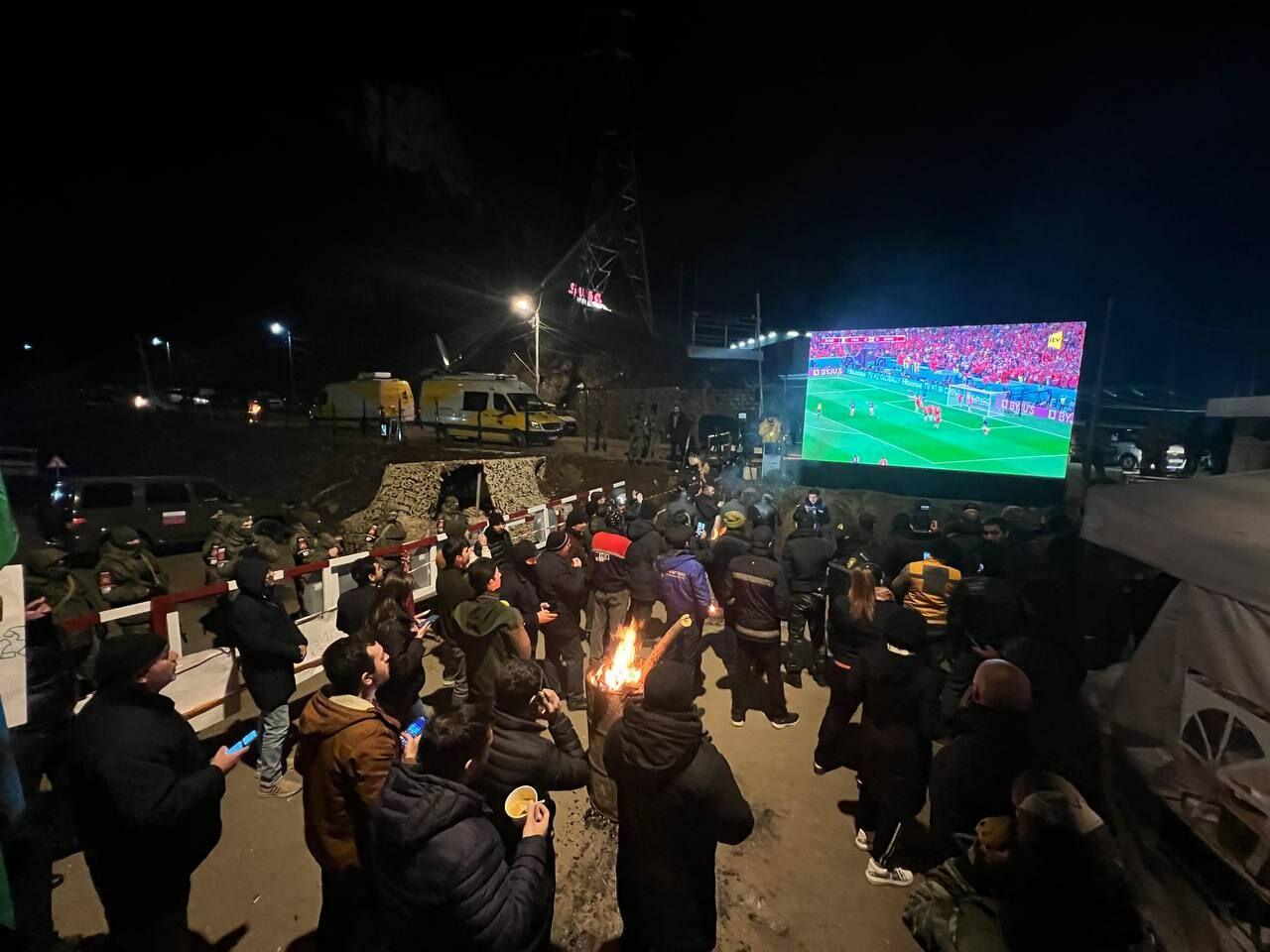 Участники акции протеста и миротворцы вместе смотрят футбольный матч Франция-Марокко