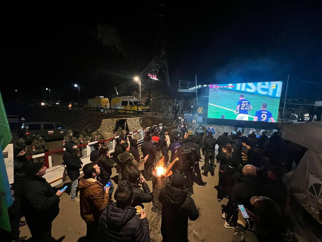 Участники акции протеста и миротворцы вместе смотрят футбольный матч Франция-Марокко